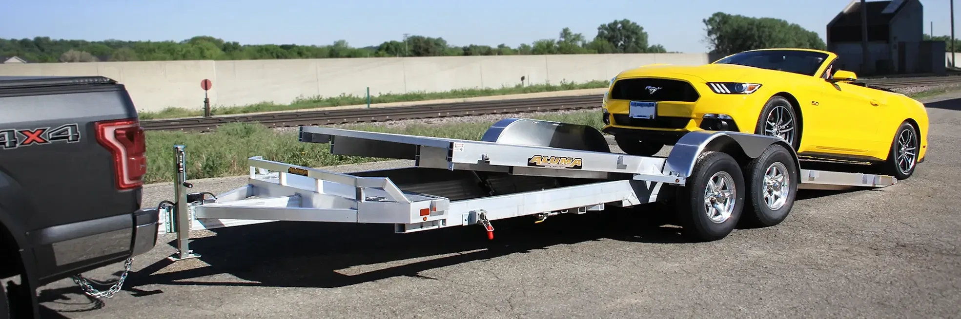 Gray truck with Aluma trailer and yellow Mustang.